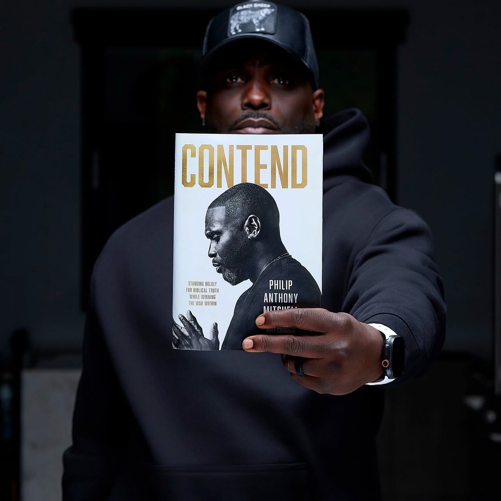Philip Anthony Mitchell holding his new book, Contend